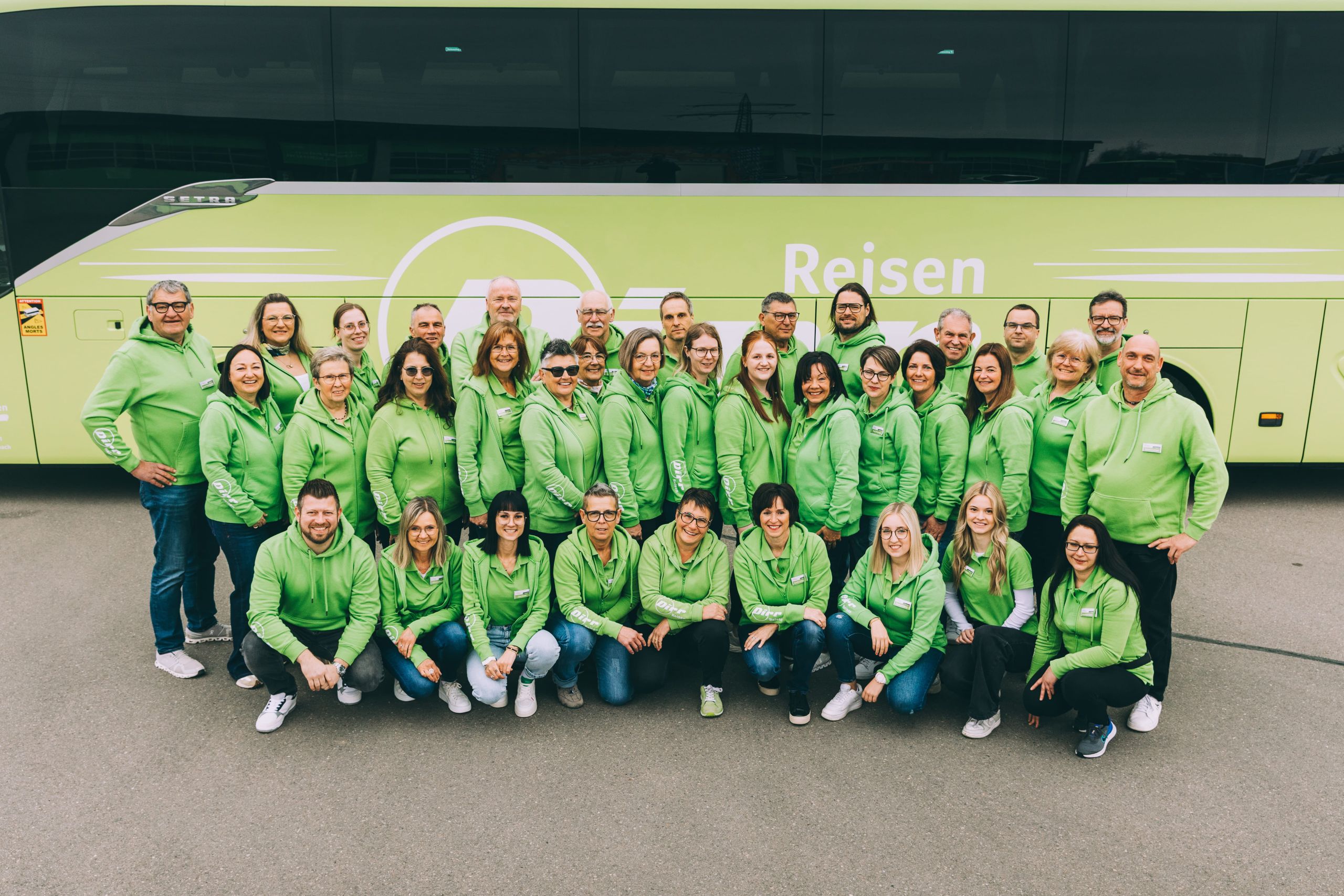 Team von Dirr-Reisen vor einem grünen Reisebus auf einer Reisemesse