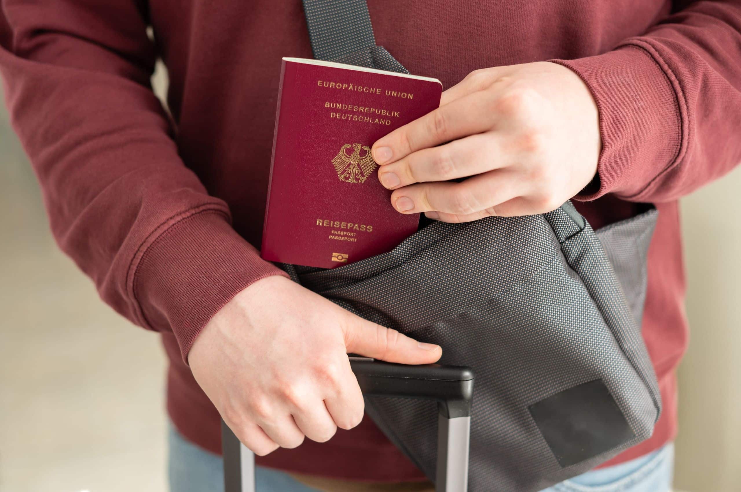 Mann nimmt Reisepass aus seiner Umhängetasche